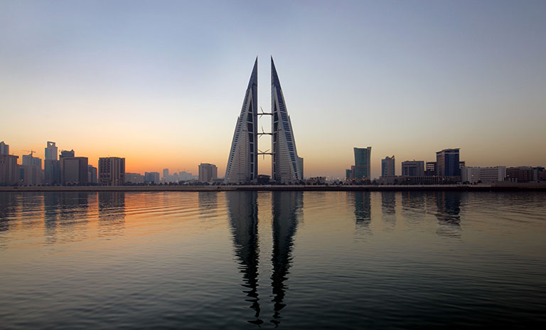 Image of a city in Bahrain with two symmetrical buildings side by side in the centre and a river in the foregrouns