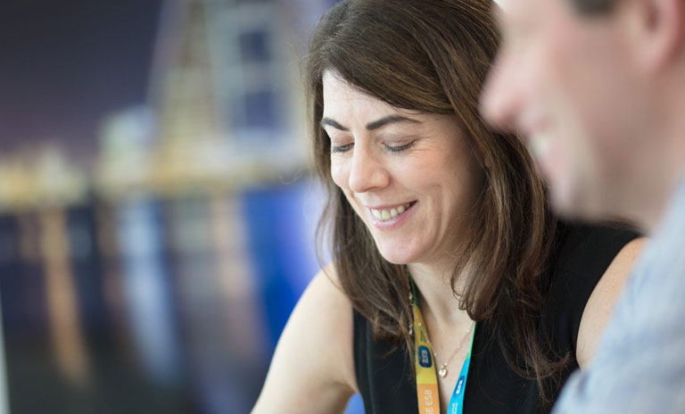 Close up photograph of a woman's face. She is smiling and looking down