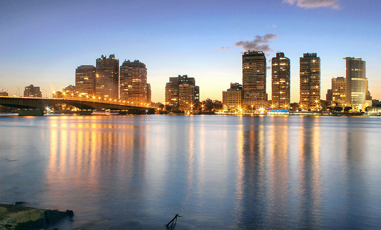 Photograph of a city skyline taken at dusk with a river in the foreground