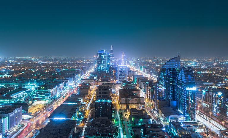 Photograph of a city skyline at night with lots of buildings