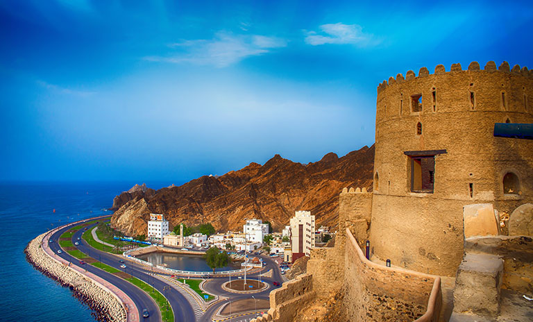 Image of a coastal road and a castle like building with a turret taken at night time