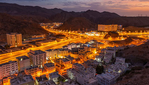 Photograph of a build up area among some mountains taken at night