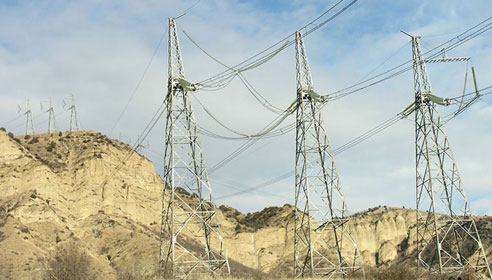 Photograph of electricity pylons on a steep rocky hill