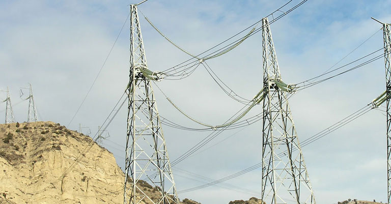 Photograph of electricity pylons on a steep rocky hill