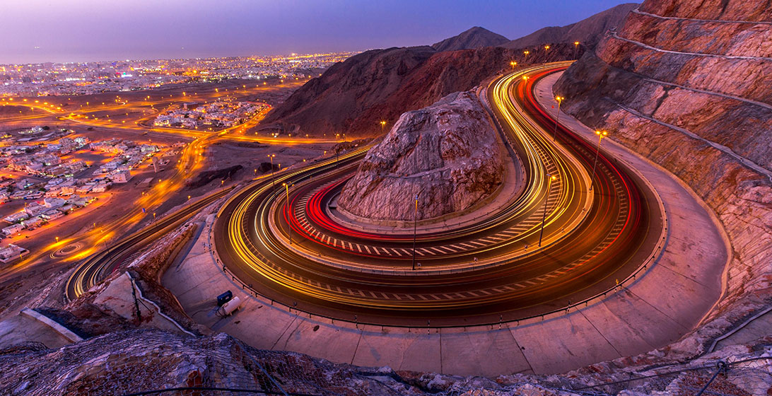 Photograph of a bend in a road set in a mountain above a city