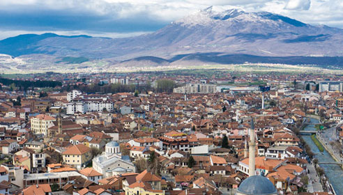 Photograph of a city in front of a large mountain