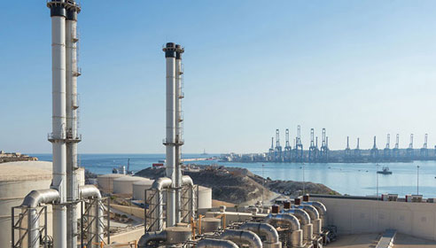 Photograph of a power station with body of water in the background