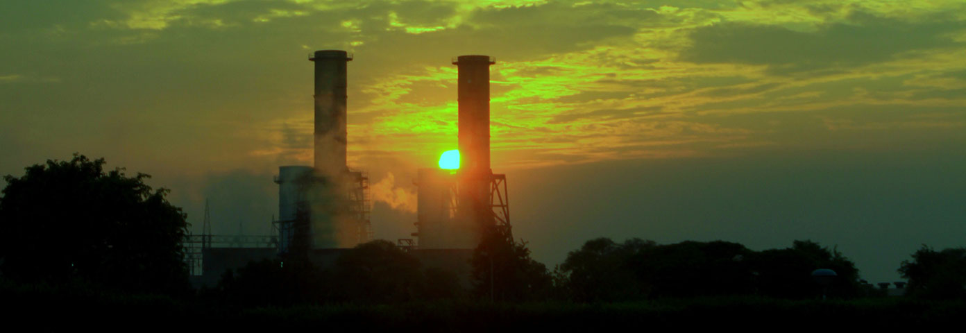 Photograph of two industrial chimneys against a setting sun