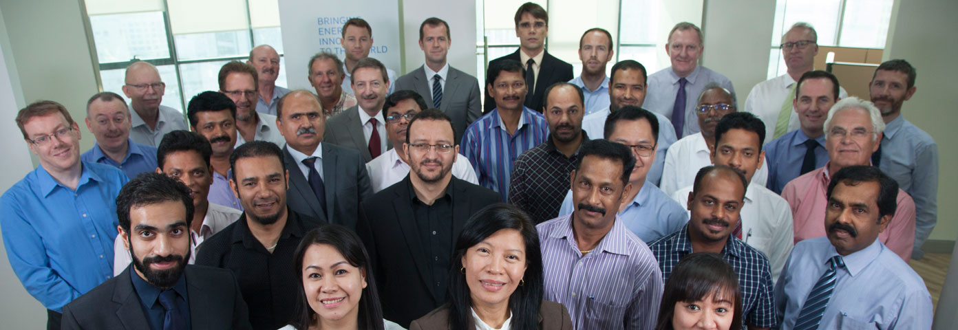 Photograph of a large group of people of different genders and ethnicities all looking at the camera