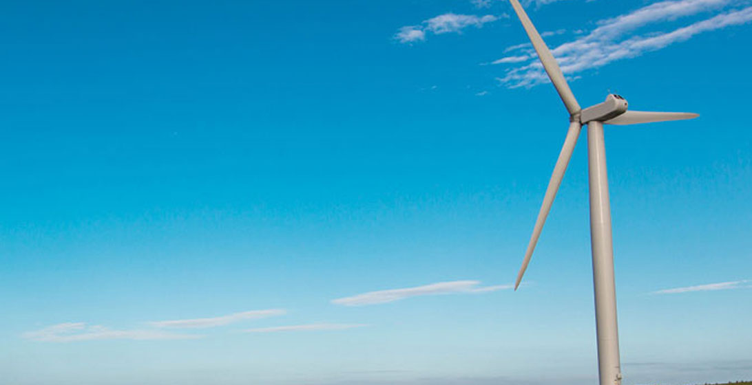 Photograph of a wind turbine with blue sky in the background